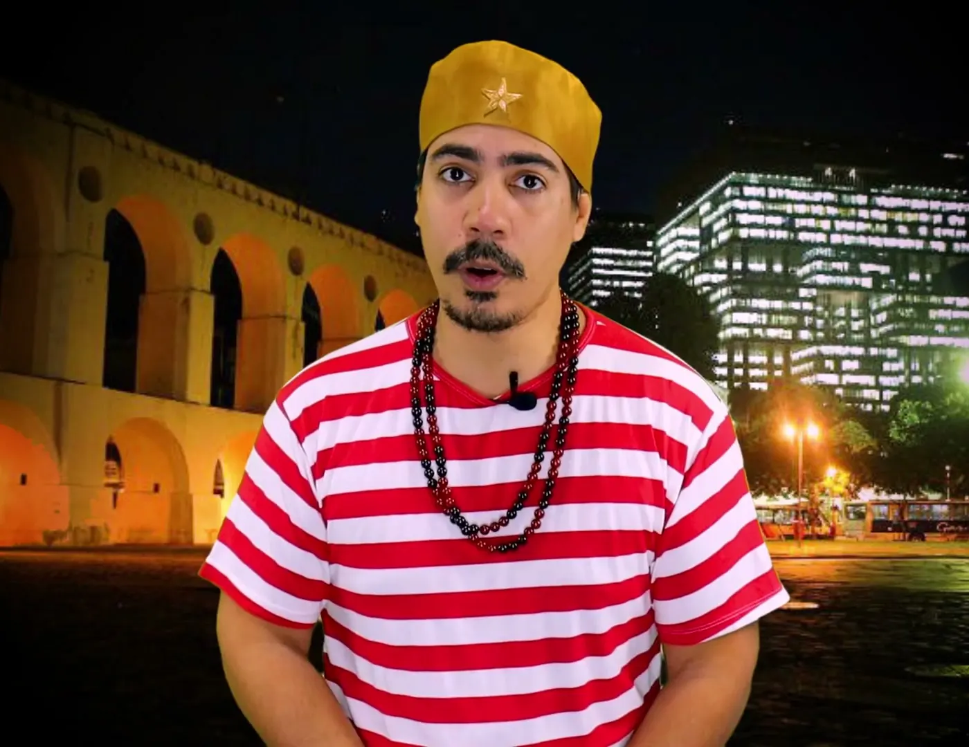 Bruno Amorim, de camisa listrada vermelha e branca, diante dos Arcos da Lapa à noite