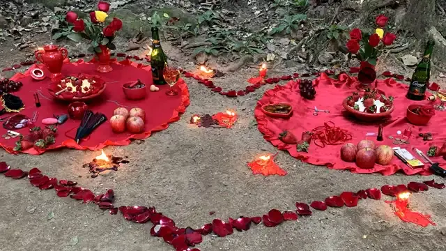 Oferendas em toalhas vermelhas, com rosas, frutas, velas e pétalas formando um coração