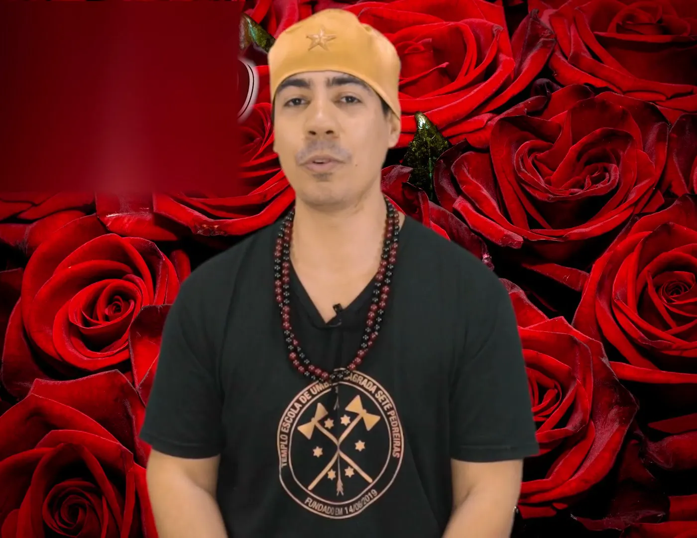 Bruno Amorim, de camiseta preta e guias vermelhas, diante de rosas vermelhas